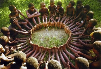 crianças sentadas no chão formando um circulo com os pés